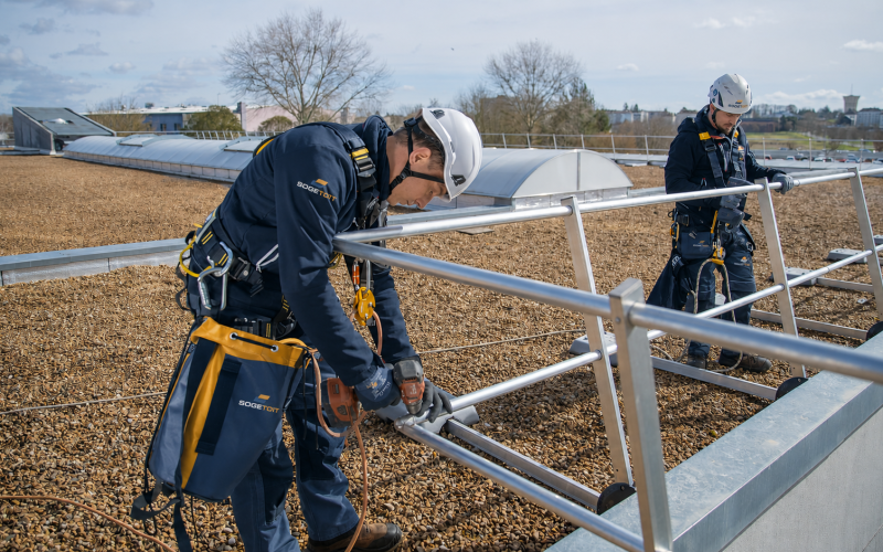 Techniciens qualifiés de l'entreprise SOGETOIT à Lons réparant des garde-corps sur une toiture plate d'un bâtiment professionnel aux alentours de Pau
